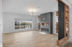 Living area featuring light wood-finish flooring and a contemporary linear fireplace with a textured tile surround - 