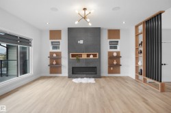 Contemporary living space featuring a tiled fireplace with built-in shelving, large windows, light wood-finish flooring, and a decorative room divider with integrated shelving - 