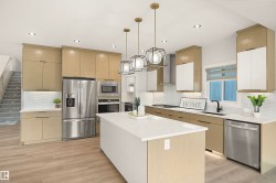 Contemporary kitchen featuring a large central island with a solid surface countertop, stainless steel appliances, two-tone cabinetry, wood-finish flooring, and recessed lighting - 