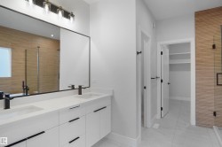 Bathroom featuring a dual-sink vanity with white cabinetry and dark hardware - 