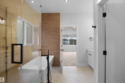Contemporary bathroom featuring a freestanding tub with a matte black floor-mounted faucet, glass shower enclosure, wood-finish accent wall, and recessed lighting - 162 Edgewater Circle, Leduc, AB - Indoor