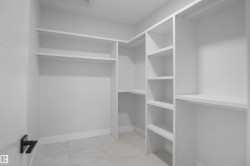 Walk-in closet featuring built-in shelving, multiple hanging rods, and large format floor tiling - 