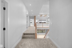Carpeted upper-level hallway with recessed lighting and white walls - 
