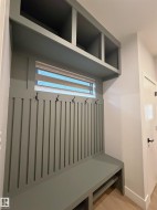 Built-in mudroom bench with vertical slat paneling, integrated storage cubbies, and overhead shelving - 