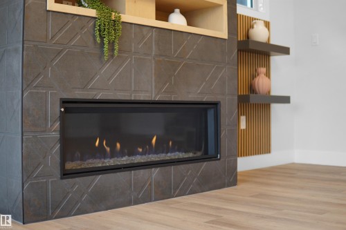 Modern fireplace featuring a dark geometric tile surround and a linear glass-front insert - 162 Edgewater Circle, Leduc, AB - Indoor With Fireplace