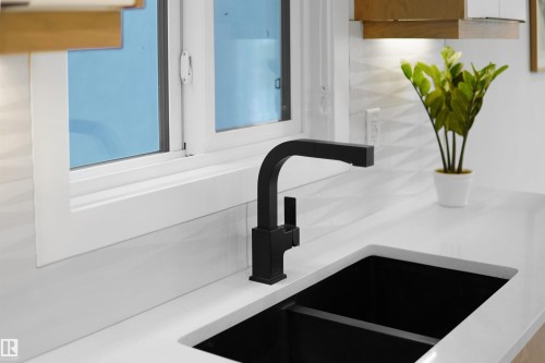 Matte black faucet over a deep black undermount sink, set into a white countertop - 162 Edgewater Circle, Leduc, AB - Indoor Photo Showing Kitchen With Double Sink