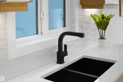 Matte black faucet over a deep black undermount sink, set into a white countertop - 