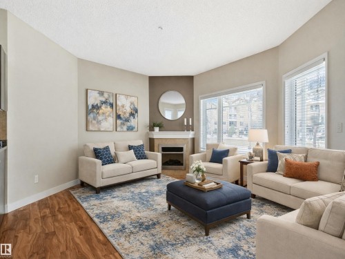 Living room featuring hardwood style flooring, a corner fireplace with a mantel, and large windows with blinds - 120 8931 156 Street, Edmonton, AB - Indoor Photo Showing Living Room With Fireplace