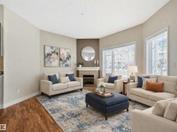 Living room featuring hardwood style flooring, a corner fireplace with a mantel, and large windows with blinds - 
