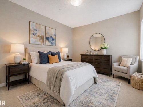 This bedroom features light-colored carpeting, a bed with a fabric headboard, and two dark wood nightstands with lamps - 120 8931 156 Street, Edmonton, AB - Indoor Photo Showing Bedroom