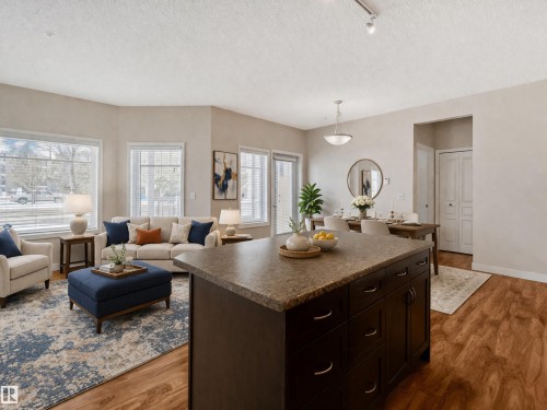 Open-concept living area featuring hardwood flooring, an inviting living room with ample natural light from large windows, and a dedicated dining space - 120 8931 156 Street, Edmonton, AB - Indoor Photo Showing Living Room