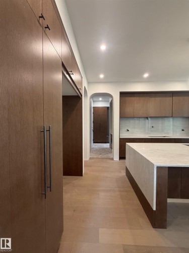 Kitchen featuring wood-finish cabinetry with matte black hardware, a large central island with a waterfall countertop, recessed lighting, and light wood-finish flooring - 14702 Park Drive, Edmonton, AB - Indoor