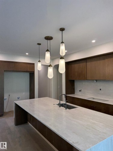 Expansive kitchen island with a light-toned stone surface, integrated sink, and matte black faucet - 14702 Park Drive, Edmonton, AB - Indoor Photo Showing Kitchen
