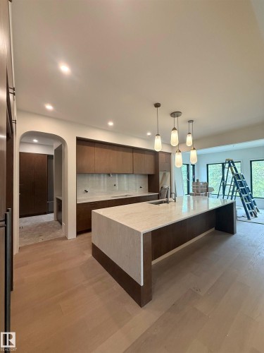 Kitchen featuring a waterfall island with stone countertop, dark wood-finish cabinetry, and pendant lighting - 14702 Park Drive, Edmonton, AB - Indoor Photo Showing Kitchen