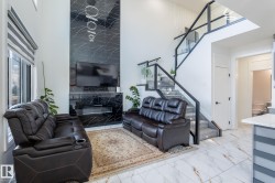 Two-story living area featuring a black marble-look fireplace surround, a built-in electric fireplace, and a television recess - 