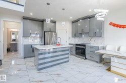 Modern kitchen featuring high-gloss gray cabinetry, stainless steel appliances, a center island with a white countertop and contrasting striped paneling, and white marble-look flooring extending throughout - 