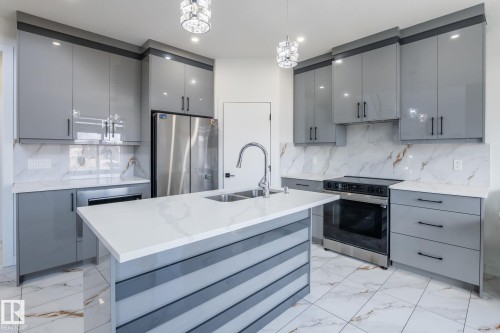 Modern kitchen featuring a central island with an undermount sink and gooseneck faucet - 6607 50A Avenue, Beaumont, AB - Indoor Photo Showing Kitchen With Stainless Steel Kitchen With Double Sink With Upgraded Kitchen