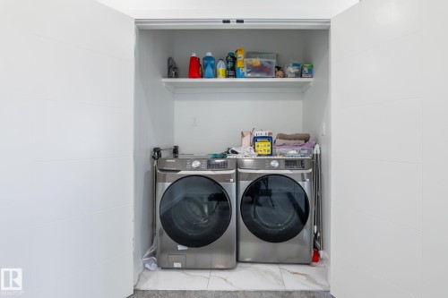 Dedicated laundry closet featuring a built-in shelf, white walls, and a tiled floor - 6607 50A Avenue, Beaumont, AB - Indoor Photo Showing Laundry Room