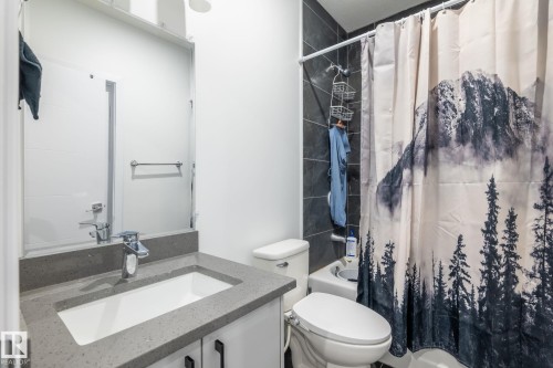Modern bathroom featuring a single vanity with a light gray countertop and undermount sink - 6607 50A Avenue, Beaumont, AB - Indoor Photo Showing Bathroom