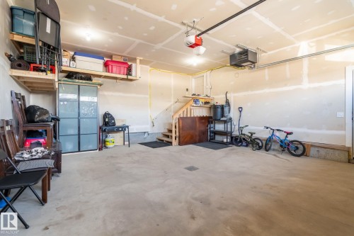Spacious garage featuring a concrete floor, built-in overhead shelving, and a finished ceiling with recessed lighting - 6607 50A Avenue, Beaumont, AB - Indoor Photo Showing Garage