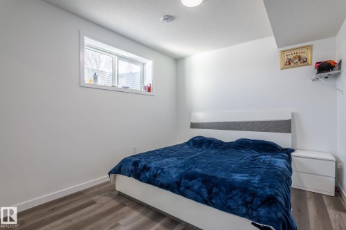 Bedroom featuring wood-finish flooring, a white baseboard, a window with white trim, a recessed ceiling light, and a smoke detector - 6607 50A Avenue, Beaumont, AB - Indoor Photo Showing Bedroom