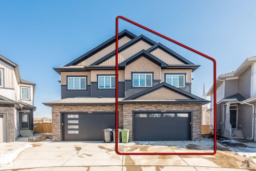 Modern two-story duplex featuring a multi-textured facade with stone veneer, horizontal siding, and shake siding - 6607 50A Avenue, Beaumont, AB - Outdoor With Facade