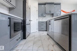 Modern kitchen featuring white tile flooring with brown veining, light gray cabinetry, built-in stainless steel microwave, and integrated stainless steel dishwasher - 