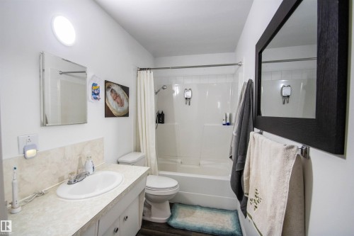 Bathroom featuring a single-sink vanity with light-toned countertop, white toilet, and a white shower-tub combination - 5125 46 Ave, St. Paul Town, AB - Indoor Photo Showing Bathroom
