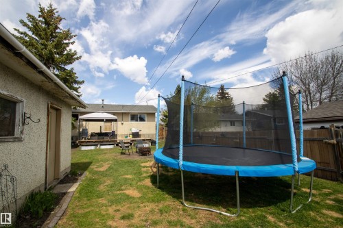 Expansive backyard featuring a large green space, a multi-level wooden deck with a white gazebo, a detached stucco structure, and mature perimeter trees - 5125 46 Ave, St. Paul Town, AB - Outdoor With Exterior