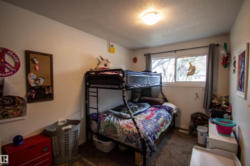 Room featuring a window with gray drapes, overhead flush mount lighting, and textured carpeting - 5125 46 Ave, St. Paul Town, AB - Indoor Photo Showing Bedroom