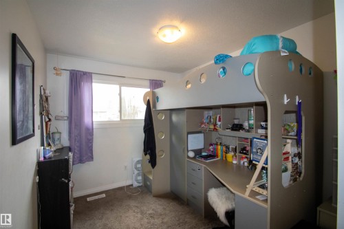 Room featuring a window, carpet flooring, a ceiling-mounted light fixture, and a built-in loft bed with integrated desk and shelving - 5125 46 Ave, St. Paul Town, AB - Indoor