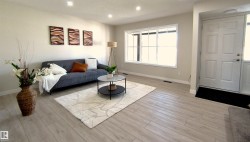 Spacious living area featuring light wood-finish flooring, recessed lighting, and a prominent large window with white trim - 