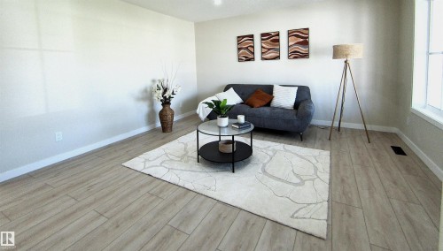 Spacious room featuring light wood-finish flooring, white baseboards, and neutral wall paint - 14125 30 Street, Edmonton, AB - Indoor Photo Showing Living Room
