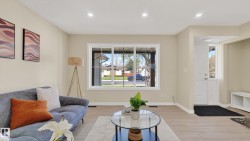 Spacious living area featuring light wood-finish flooring, recessed lighting, and a large front-facing window with white trim - 