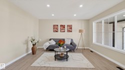 Open-concept living space with light neutral wall tones and wood-finish flooring - 