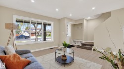 Spacious living area featuring a large picture window, recessed lighting, light wood-finish flooring, and a built-in entryway bench with coat hooks - 