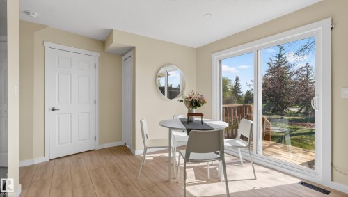 Dining area featuring wood-finish flooring, light-toned walls, and a white six-panel door - 14125 30 Street, Edmonton, AB - Indoor
