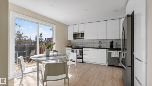 Bright kitchen featuring white cabinetry, dark countertops, and stainless steel appliances - 14125 30 Street, Edmonton, AB - Indoor Photo Showing Kitchen With Upgraded Kitchen