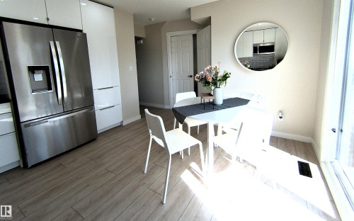 Open-concept dining area featuring wood-finish flooring, a contemporary ceiling light fixture, and a large sliding glass door - 14125 30 Street, Edmonton, AB - Indoor Photo Showing Dining Room