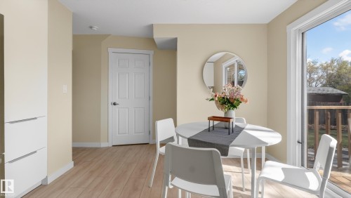Dining area featuring wood-finish flooring, light-toned walls, and a sliding glass door providing exterior access - 14125 30 Street, Edmonton, AB - Indoor Photo Showing Dining Room