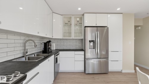 Contemporary kitchen featuring white high-gloss cabinetry, dark countertops, and a white subway tile backsplash - 14125 30 Street, Edmonton, AB - Indoor Photo Showing Kitchen With Double Sink With Upgraded Kitchen