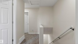 Upper-level hallway featuring neutral wall tones, white trim, and a low-pile carpet - 