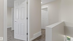 Upper-level hallway featuring neutral wall paint, white six-panel doors, and gray carpet flooring - 
