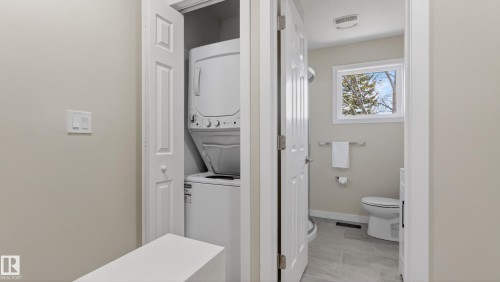 Compact laundry closet featuring a stackable washer and dryer - 14125 30 Street, Edmonton, AB - Indoor Photo Showing Laundry Room