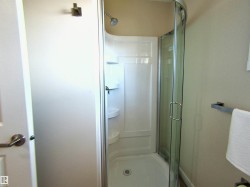 Corner shower stall featuring a curved glass enclosure, built-in shelving, and a silver-finish showerhead - 