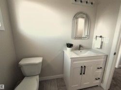 Bathroom featuring a contemporary vanity with white cabinetry and black hardware - 