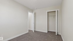 Room featuring neutral-toned walls, grey carpet, white trim, and a white interior door - 