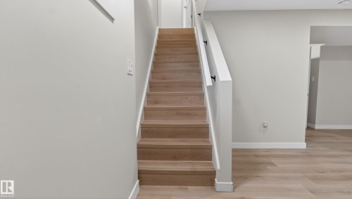 Staircase featuring wood-finish treads and white risers, complemented by a white handrail with black supports - 14125 30 Street, Edmonton, AB - Indoor Photo Showing Other Room