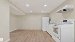 Open-concept living area with wood-finish flooring, recessed lighting, and a white appliance suite - 