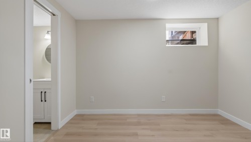 Light wood-finish flooring complements neutral wall tones and white baseboards - 14125 30 Street, Edmonton, AB - Indoor Photo Showing Other Room